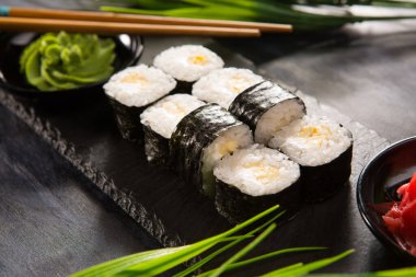 Siyah arka planda wasabi ve zencefilli suşi ruloları. Japon Doğu mutfağı.