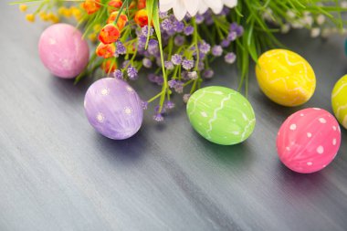 Gri ahşap arka planda çiçekli renkli paskalya yumurtaları.