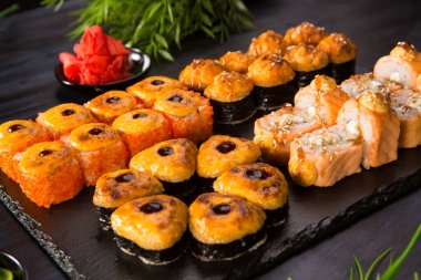 Siyah arka planda wasabi ve zencefilli fırında suşi ruloları. Japon Doğu mutfağı.