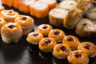 Siyah arka planda wasabi ve zencefilli fırında suşi ruloları. Japon Doğu mutfağı.