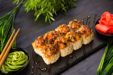 Siyah arka planda wasabi ve zencefilli fırında suşi ruloları. Japon Doğu mutfağı.