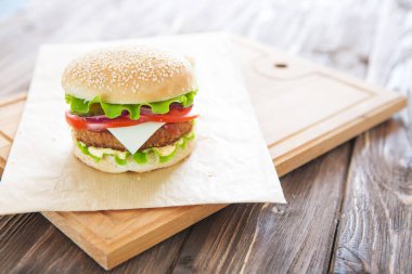 Lezzetli fast food. Ev yapımı, peynirli ve sebzeli sığır burger..