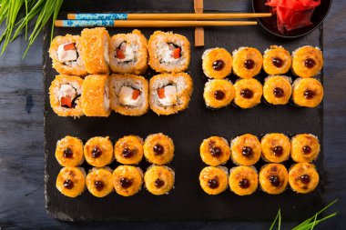 Siyah arka planda wasabi ve zencefilli fırında suşi ruloları. Japon Doğu mutfağı.