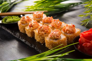 Siyah arka planda wasabi ve zencefilli fırında suşi ruloları. Japon Doğu mutfağı.