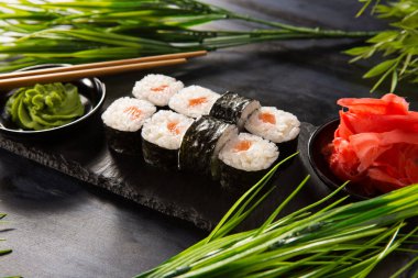 Siyah arka planda wasabi ve zencefilli suşi ruloları. Japon Doğu mutfağı.
