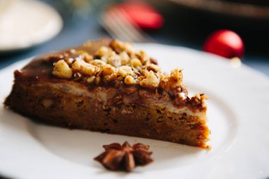 Bir parça Noel çikolatalı cevizli pasta, seçici odak noktası Glüten ücretsiz Noel fındıklı kek gri bir masa üzerinde Noel süslemeleri