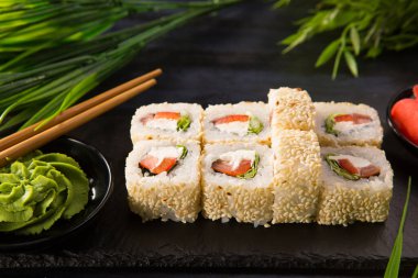 Siyah arka planda wasabi ve zencefilli suşi ruloları. Japon Doğu mutfağı.