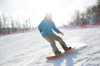 Yüksek dağlarda snowboardcu kayak yapıyor. Snowboard sporcuları, karlı yamaçların üzerinden uçakla indikten sonra denge kurarlar.