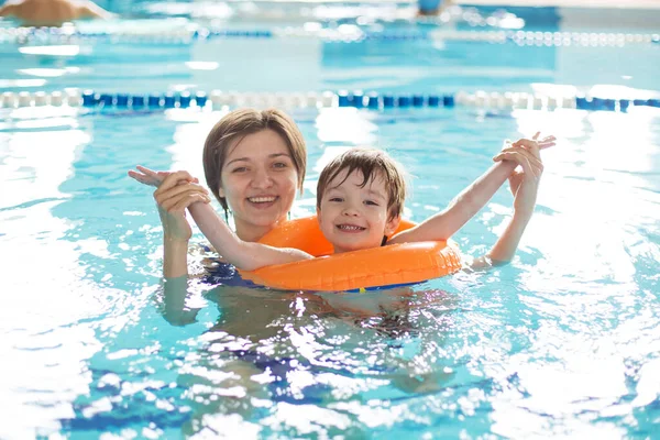 Anne bir çocuğa havuzda yüzmeyi öğretiyor. Sağlıklı aile annesi bebeğe yüzme havuzu öğretiyor.