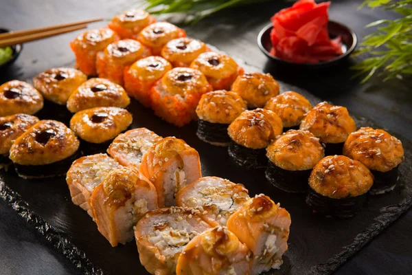 Siyah arka planda wasabi ve zencefilli fırında suşi ruloları. Japon Doğu mutfağı.