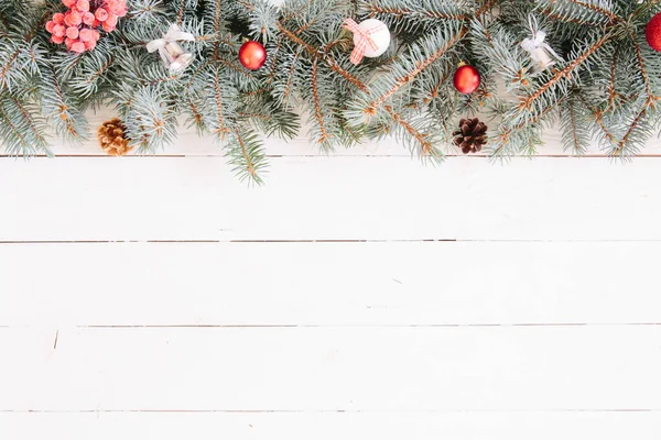 Bulanık Noel arkaplanı, köknar dalları, peri ışıkları ve beyaz tahta üzerinde noel süslemeleri.