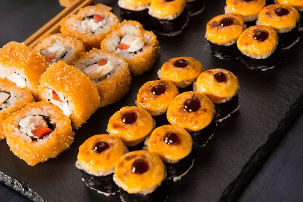 Siyah arka planda wasabi ve zencefilli fırında suşi ruloları. Japon Doğu mutfağı.
