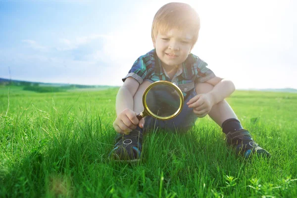 Get to know the world. Everything is incredible near you. Happy little boy exploring nature with magnifying glass at the day time.