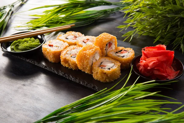 Siyah arka planda wasabi ve zencefilli fırında suşi ruloları. Japon Doğu mutfağı.