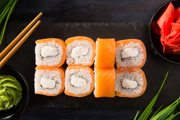 Siyah arka planda wasabi ve zencefilli suşi ruloları. Japon Doğu mutfağı.