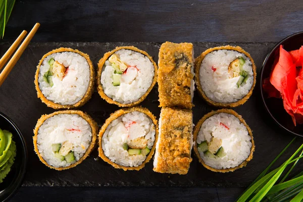 Siyah arka planda wasabi ve zencefilli fırında suşi ruloları. Japon Doğu mutfağı.