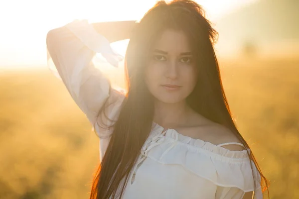 Summer is a great dream time. Young gentle woman relaxing in sunset light beam. Full lenght portrait in flower field.