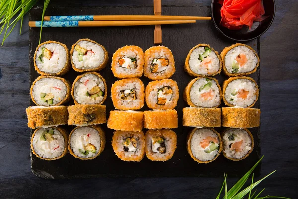 Siyah arka planda wasabi ve zencefilli fırında suşi ruloları. Japon Doğu mutfağı.