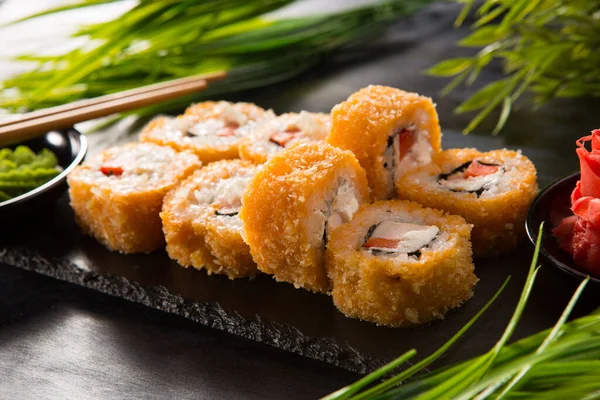 Siyah arka planda wasabi ve zencefilli fırında suşi ruloları. Japon Doğu mutfağı.