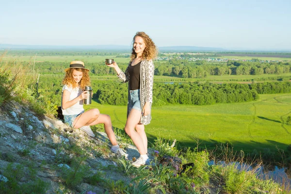 Sınırları olmayan bir dünya. Dağlarda iki kızın çarpıcı yolculuğu. Mutlu gezgin genç çift dağlarda dinleniyor ve bahar veya yaz mevsiminde gün batımında termostan çay içiyorlar..