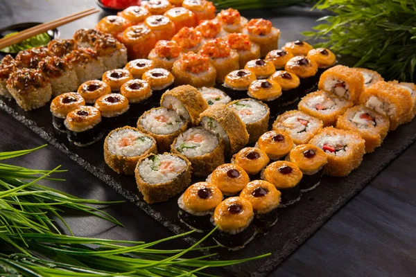 Siyah arka planda wasabi ve zencefilli fırında suşi ruloları. Japon Doğu mutfağı.