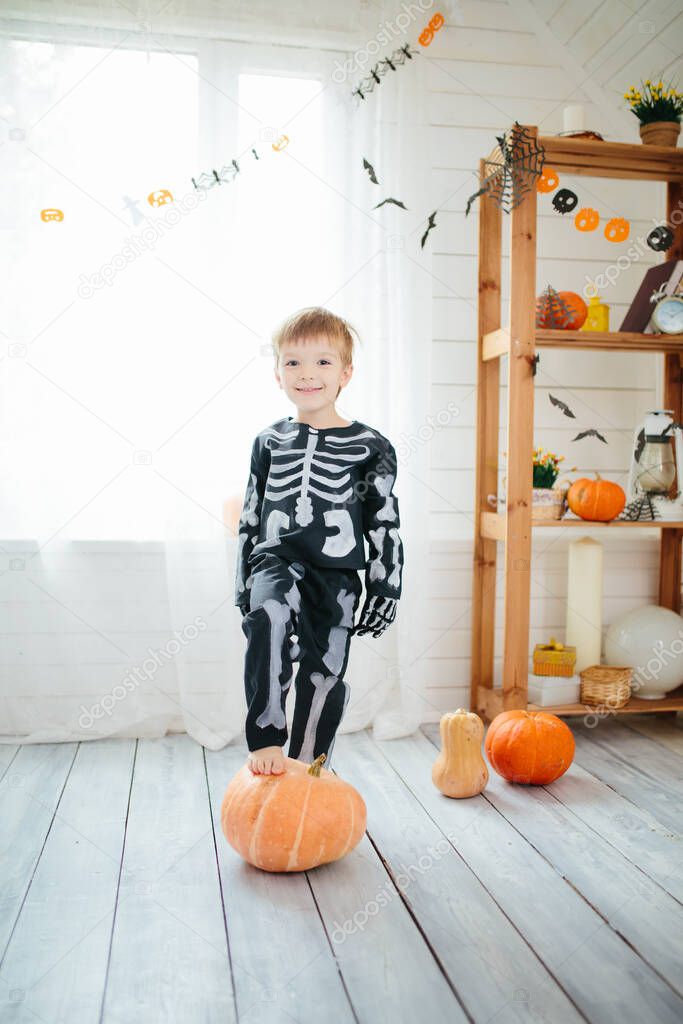 The little boy in a skeleton costume is ready to celebrate Halloween. Boy in a halloween dress-up room. .