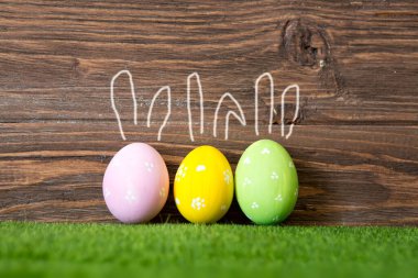 Ahşap bir zemine karşı Paskalya yumurtaları. Elle çizilmiş üç Paskalya yumurtası Tavşan kulağı.