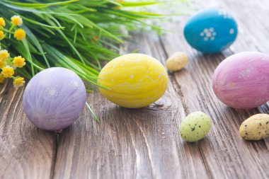 Paskalya yumurtaları ve bahar çiçekleri eski ahşap bir arka planda.