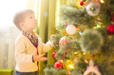 Odada Noel ağacı süsleyen sevimli küçük bir çocuk. Noel ya da yeni yıl tatili.