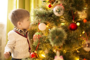 Evde Noel ağacı süsleyen küçük çocuk..