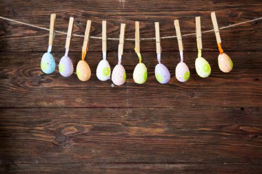 Kahverengi bir ahşap duvarda asılı duran paskalya yumurtaları..