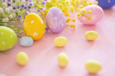 Pembe ahşap arka planda bahar çiçekleri olan Paskalya yumurtaları. Süslü yumurta tatili sanat tasarımı geçmişi. Paskalya.