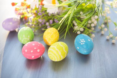 Renkli paskalya süslemesi ve gri ahşap bir masada çiçekler..