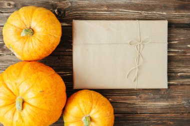 Kahverengi kâğıt pakette hediye edilmiş turuncu balkabağı. Grunge ahşap arka planda iplerle bağlanmış. Şükran Günü ve Cadılar Bayramı konsepti. Yukarıdan bak. Üst Manzara. Metin ve tasarım için boşluk kopyala