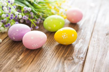 Tahta üzerinde çiçekler olan renkli paskalya yumurtaları..