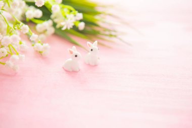 Paskalya tavşanı heykelcikleri ve tahta arka planda çiçekler..
