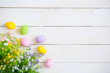 Beyaz ahşap arka planda çiçekli Paskalya yumurtaları.