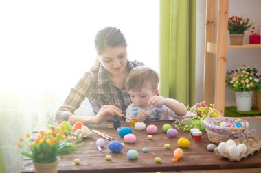 Paskalya yumurtası boyarken mutlu zamanlar. Paskalya konsepti. Mutlu anne ve tatlı çocuğu yumurtaları boyayarak Paskalya için hazırlanıyorlar..