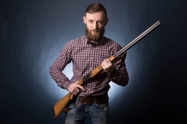 Koyu mavi arka planda elinde av tüfeği tutan bir adam..