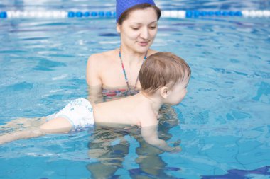 Sağlıklı bir anne bebek yüzme havuzu öğretiyor. Mutluluk ve aşk kavramı.