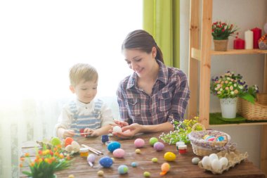 Paskalya konsepti. Mutlu anne ve tatlı çocuğu yumurtaları boyayarak Paskalya için hazırlanıyorlar..