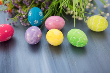 Paskalya yumurtaları ve çiçekler gri ahşap kalaslarda.