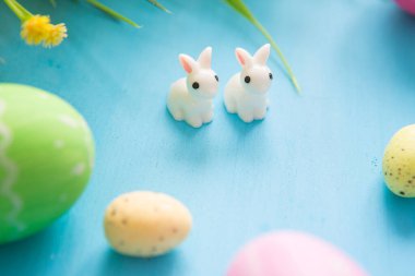 Çiçekli Paskalya yumurtaları ve tahta tahtada küçük tavşan oyuncakları, Paskalya bayramı konsepti..