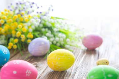 Ahşap arka planda pastel renklerle boyanmış Paskalya yumurtaları.