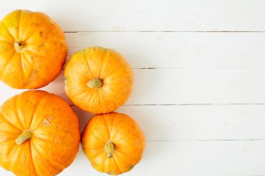 Beyaz ahşap arka planda turuncu balkabakları. Şükran Günü ve Cadılar Bayramı konsepti. Yukarıdan bak. Üst Manzara. Metin ve tasarım için boşluk kopyala