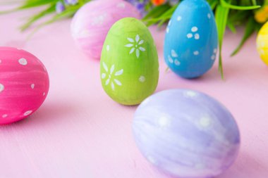 Ahşap masa arkasında kır çiçekleriyle Paskalya yumurtaları