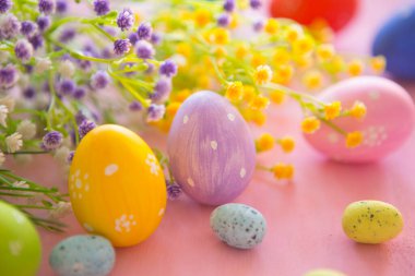 Pembe ahşap arka planda bahar çiçekleri olan Paskalya yumurtaları. Süslü yumurta tatili sanat tasarımı geçmişi. Paskalya.