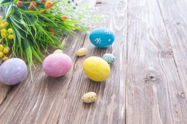 Ahşap arka planda pastel renklerle boyanmış Paskalya yumurtaları.
