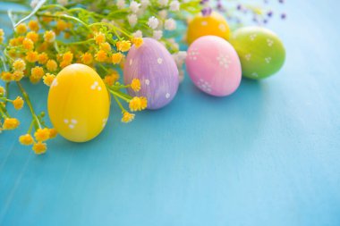 Paskalya süsü. Mavi ahşap bir masa üzerinde Paskalya yumurtası ve çiçekler.