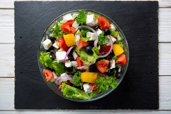 Griekse Salade Een Kom Een Zwarte Stenen Tafel Bovenaanzicht — Stockfoto